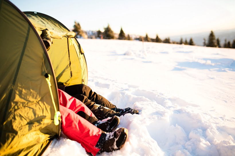 a couple sitting in a tent in winter