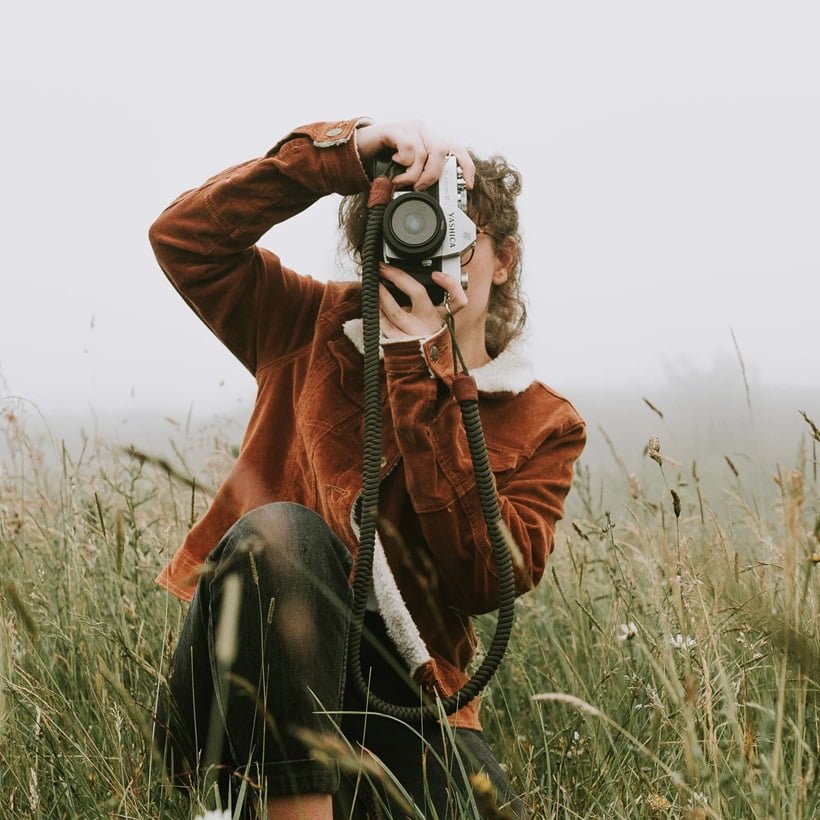 woman taking photograph in the middle of a field