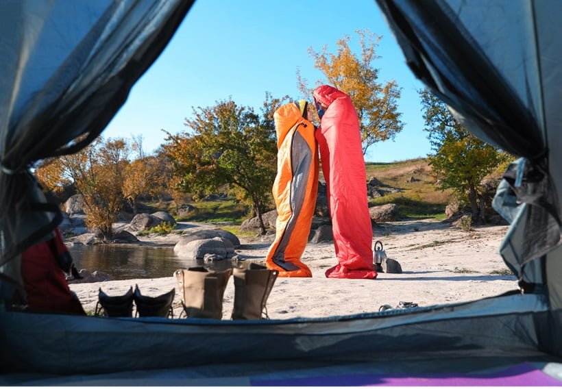couple standing with sleeping bags