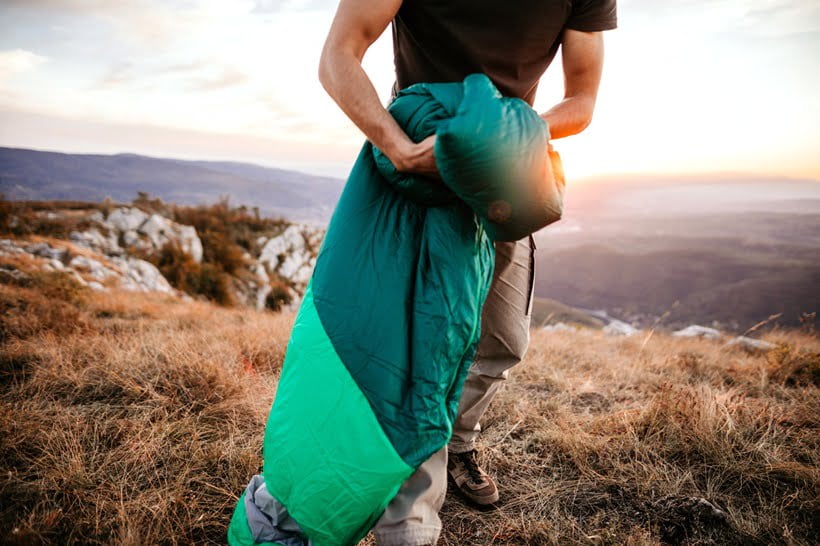 a man folding his sleeping bag