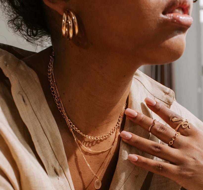 a woman wearing gold earring and necklaces