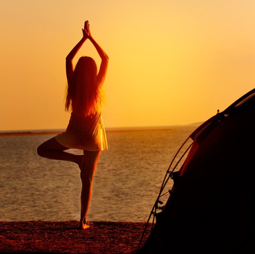 a woman doing yoga on the beach