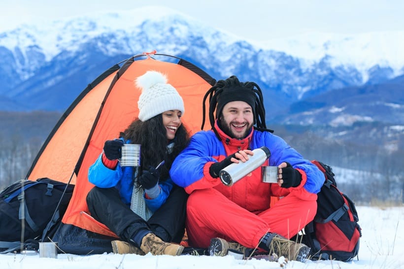couple drinking coffee in front of their tent