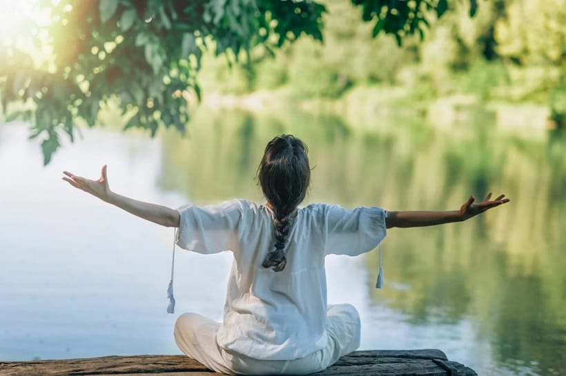 a woman meditating near lake