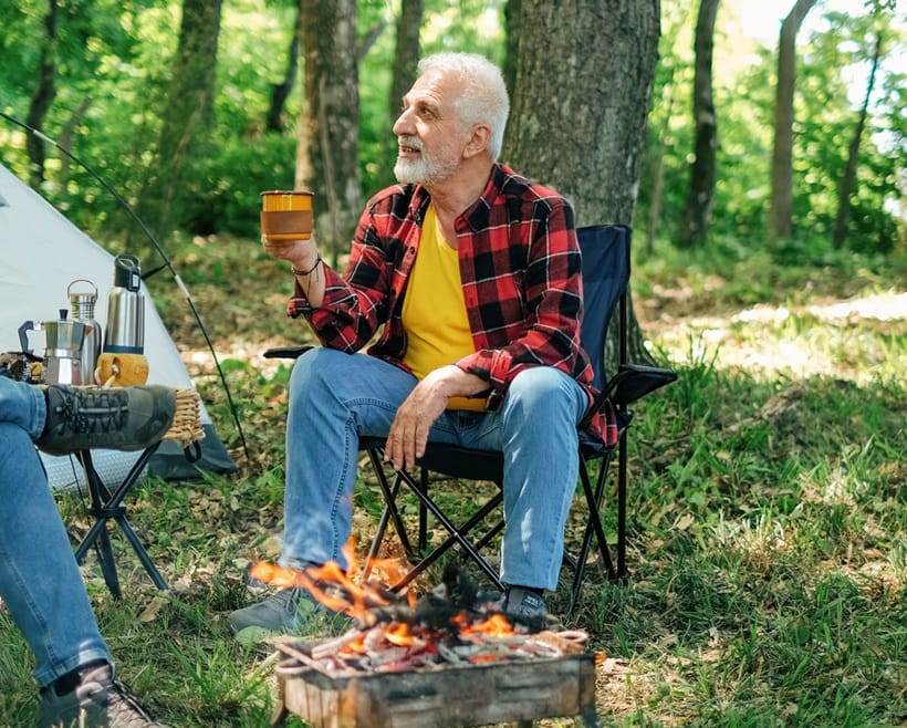 old man drinking his coffee while camping