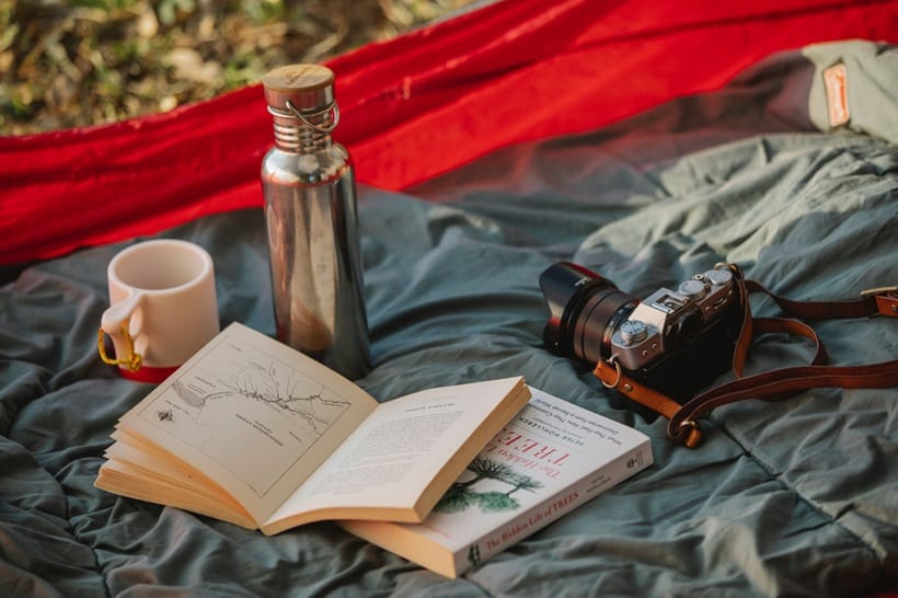 a book, a thermos, a camera and camping