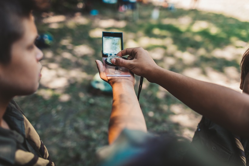 a scout using compass in a forest