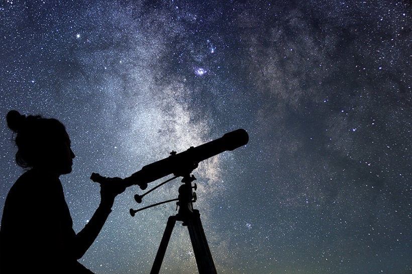 a woman observing the stars and planets with telescope